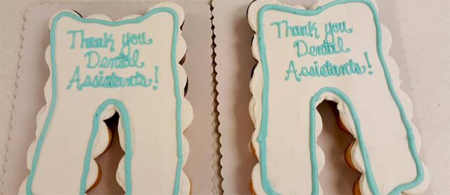 Two cakes in the shape of teeth, decorated as teeth with "Thank You Dental Assistants" written on it