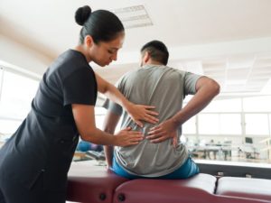 Massage therapist assessing patient with back pain