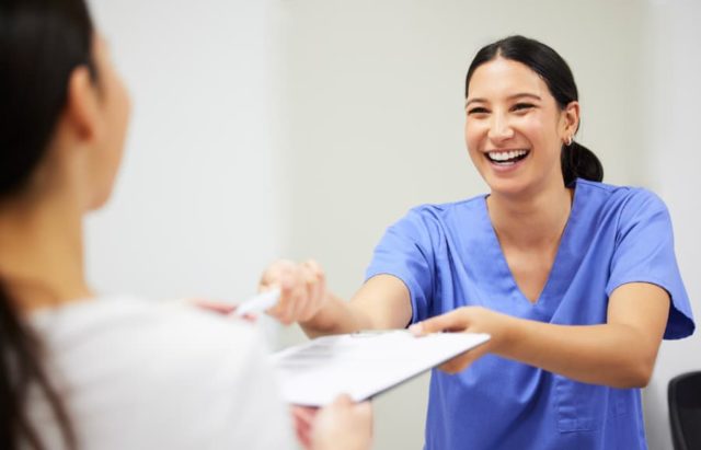 Smiling dental assistant consulting with a patient