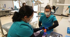 Two female dental assisting students in dental assisting class